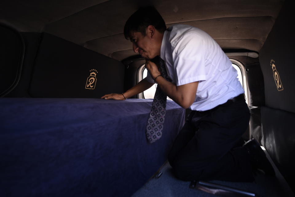 Funeral home worker Carlos Gonzalez sets an empty coffin inside a hearse outside the morgue where an autopsy is being performed on the body of English tourist Catherine Shaw in Quetzaltenango, Guatemala, Tuesday, March 12, 2019. The body of the 23-year-old who was found dead near a highland lake popular with travelers showed signs of trauma but no apparent gunshot or stab wounds, a doctor performing an autopsy said Tuesday. (AP Photo/Santiago Billy)