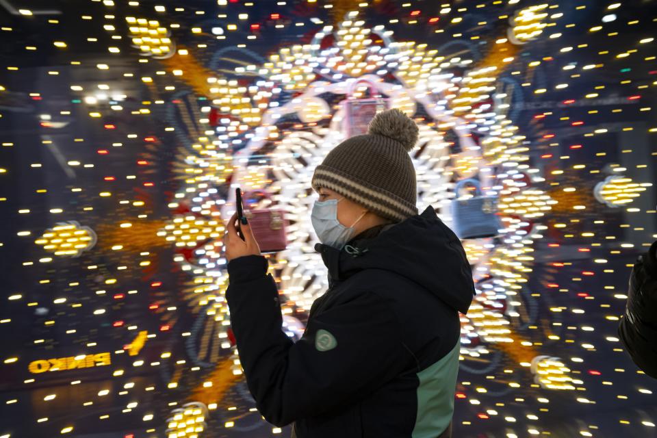 A visiter wearing a face mask to help curb the spread of the coronavirus looks at her smartphone as she walks in the GUM State Department store decorated for Christmas and New Year celebrations virtually empty due to the coronavirus pandemic in Moscow, Russia, Thursday, Dec. 3, 2020. Russia's coronavirus vaccine Sputnik V will be available for people in high-risk groups at 70 medical facilities in Moscow starting on Saturday. According to Moscow Mayor Sergei Sobyanin, those working in education and medical facilities, along with municipal workers, can get the shots. (AP Photo/Alexander Zemlianichenko)