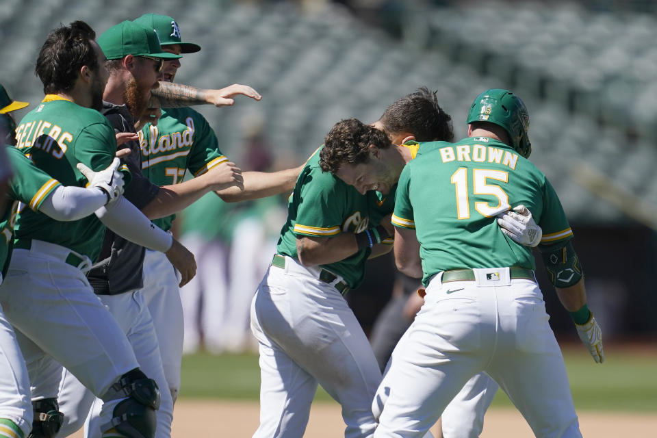 Oakland Athletics' Skye Bolt, second from right, is congratulated by teammates after hitting a sacrifice fly that scored David MacKinnon during the 10th inning of a baseball game against the Miami Marlins in Oakland, Calif., Wednesday, Aug. 24, 2022. (AP Photo/Jeff Chiu)