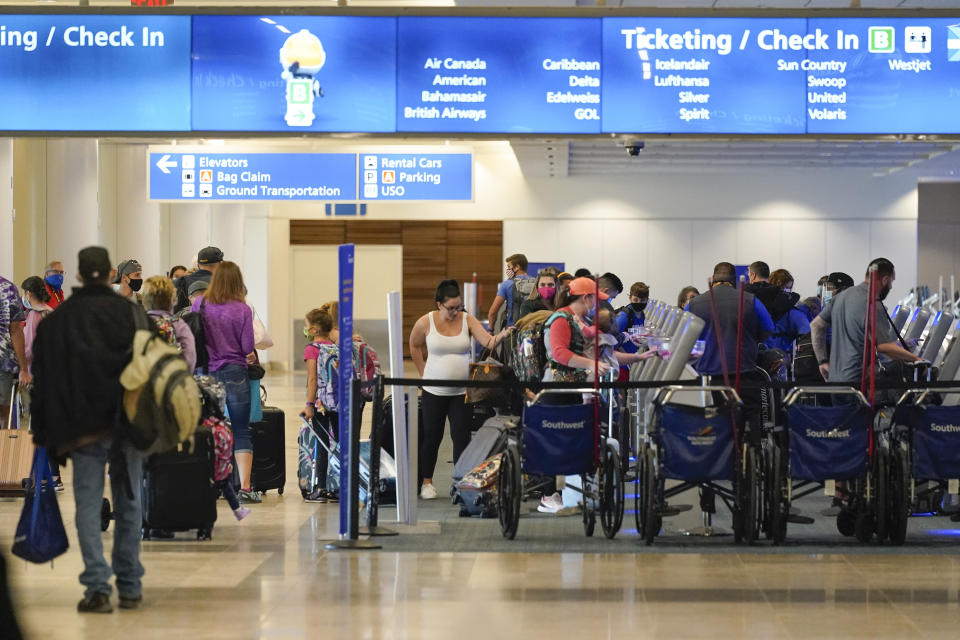 Holiday travelers check in at kiosks near an airline counter at Orlando International Airport Tuesday, Nov. 24, 2020, in Orlando, Fla. (AP Photo/John Raoux)