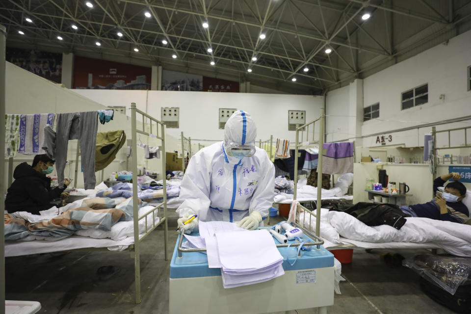 In this Feb. 18, 2020, photo, a medical staff member works near COVID-19 patients recuperating in a temporary hospital converted from an exhibition center in Wuhan in central China's Hubei province. The hospital, one of the dozen of its kind built in Wuhan, hosts COVID-19 patients with mild symptoms. (Chinatopix via AP)
