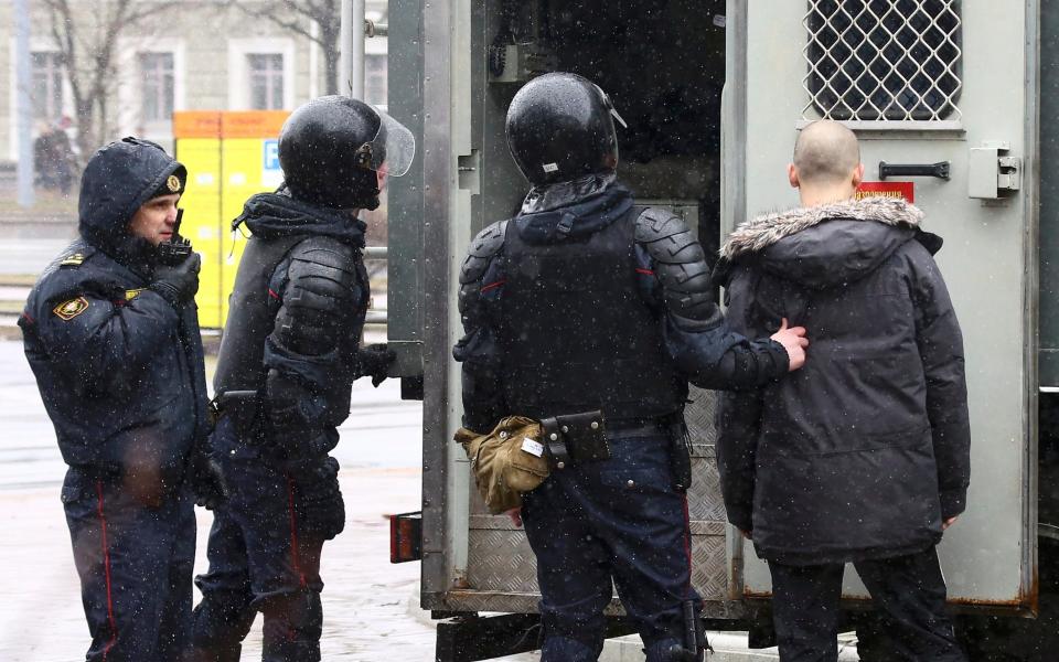 Law enforcement officers detain a man during a gathering, denouncing the new tax on those not in full-time employment - Credit: AP