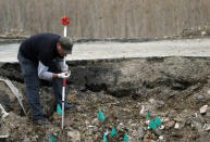 A forensic expert inspects an object found at a mass grave site in the village of Rudnica, 280 kilometers (170 miles) south of Belgrade, Serbia, Wednesday, April 23, 2014, wehre at least 250 bodies of ethnic Albanian victims of the 1998 - 99 Kosovo war are believed to be buried. Some 10,000 people were killed during the conflict between Serbian security troops and Kosovo separatists, and The Serbian government official dealing with the wartime missing, Veljko Odalovic, said Wednesday that the exhumation in the village of Rudnica, will take about 60 days. (AP Photo/Darko Vojinovic)
