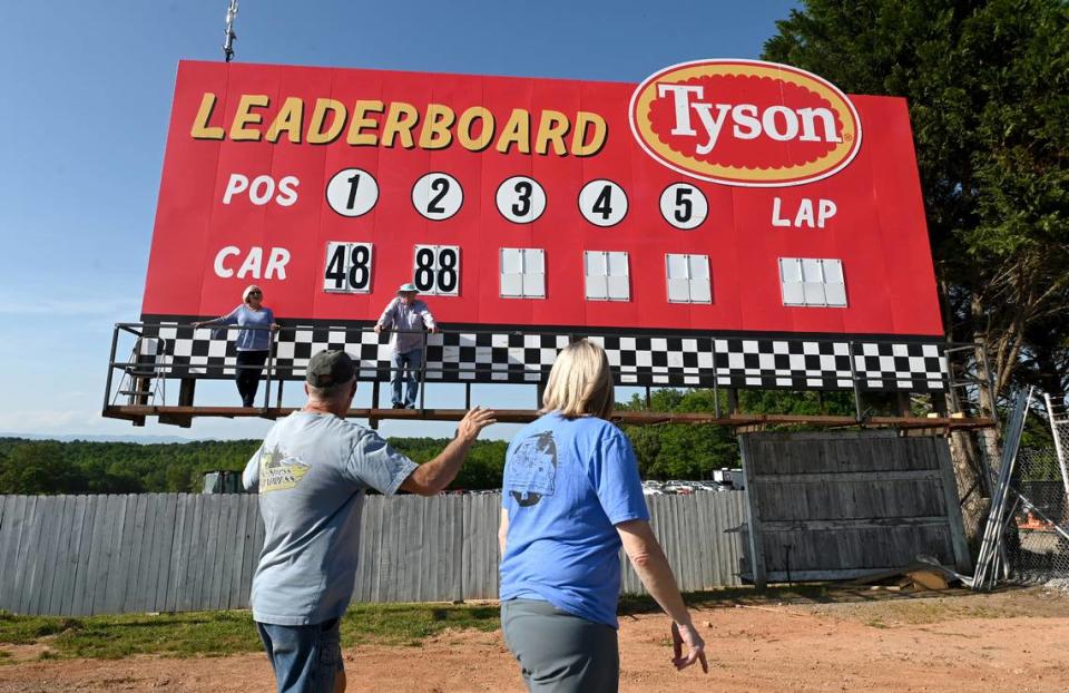 Judy and Ken Brooks stand on the leaderboard platform as fans pass by at North Wilkesboro Speedway on Wednesday, May 10, 2023. The speedway will host the NASCAR All-Star race on Sunday, May 21, 2023. The couple operated the manual leaderboard during the last race ran at the speedway in 1996.