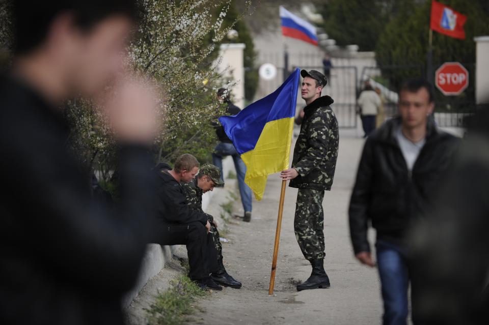 A Ukrainian serviceman holds a Ukrainian flag before leaving the Belbek airbase near Sevastopol, Crimea, Friday, March 28, 2014. Ukraine started withdrawing its troops and weapons from Crimea, now controlled by Russia. Russia's president says Ukraine could regain some arms and equipment of military units in Crimea that did not switch their loyalty to Russia. (AP Photo/Andrew Lubimov)