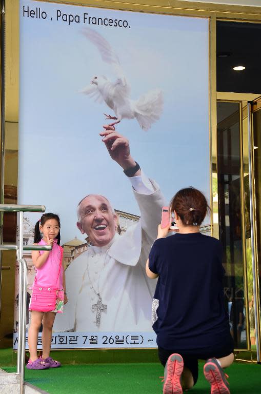 A girl poses in with a poster advertising a Pope Francis photo exhibition in Seoul on August 8, 2014