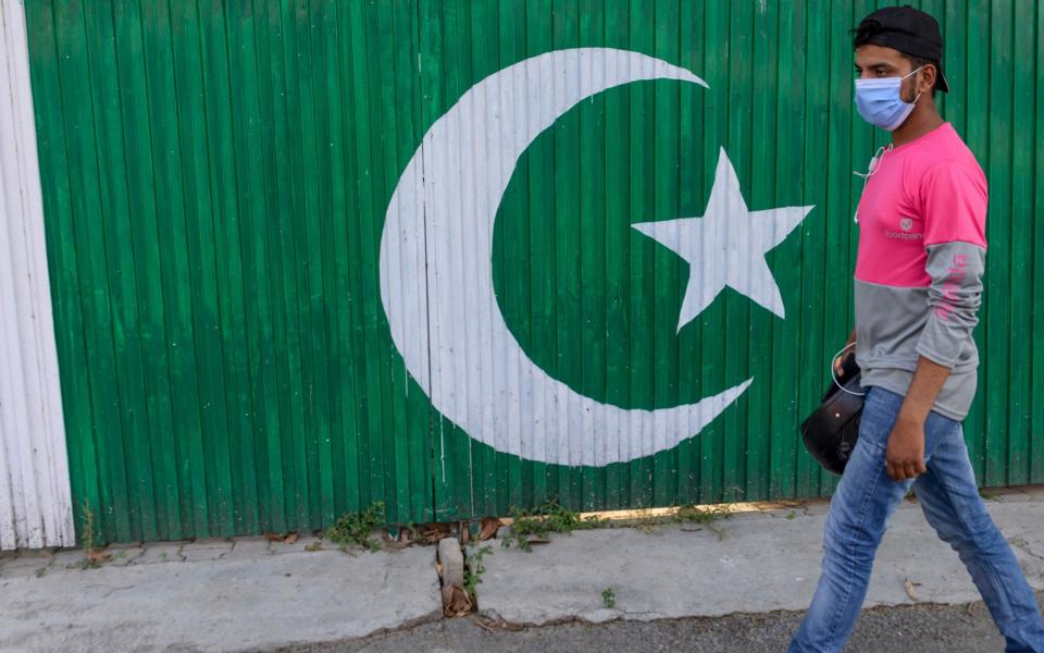 A food delivery boy walks past a hotel gate painted with Pakistan's national flag on a street in Rawalpindi on June 6 - AFP