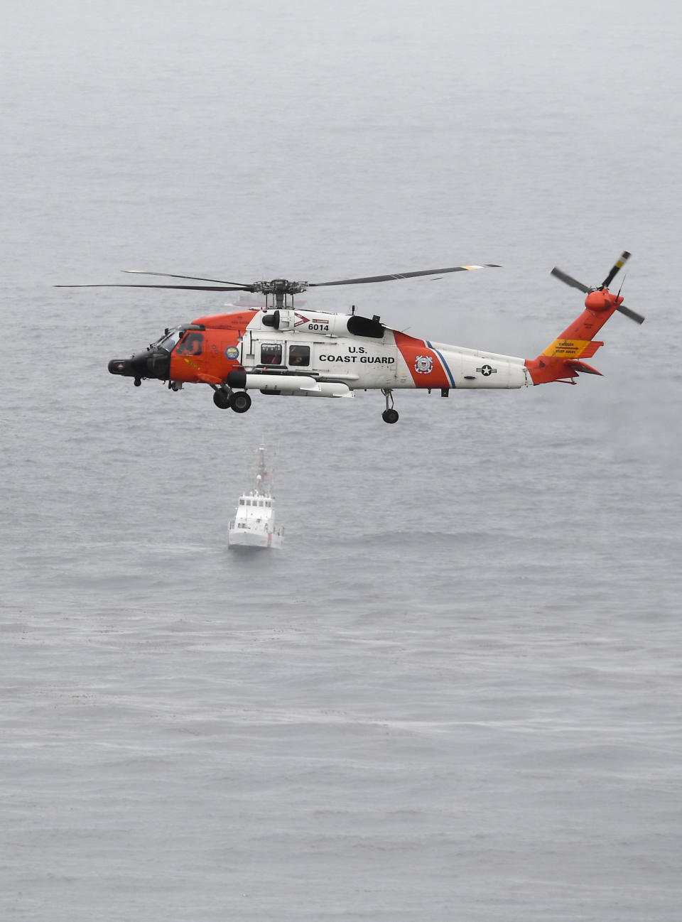 A U.S. Coast Guard helicopter flies over boats searching the area where a boat capsized just off the San Diego coast Sunday, May 2, 2021, in San Diego. (AP Photo/Denis Poroy)