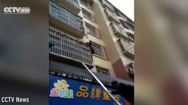 The man is seen climbing up a steel pole after spotting the child dangling by its neck. Photo: CCTV