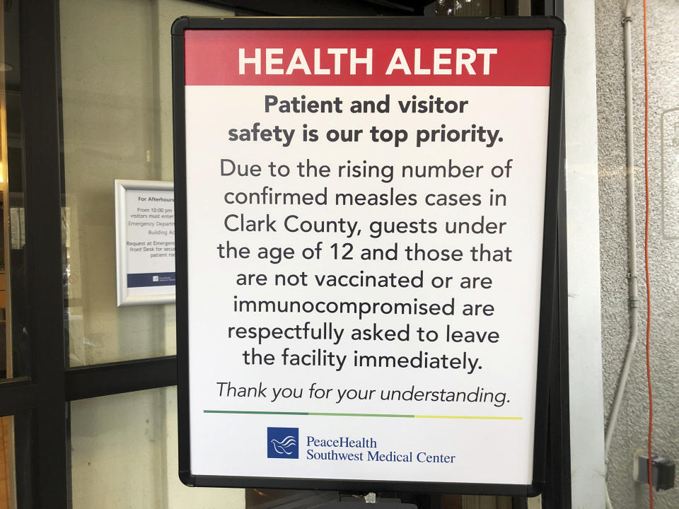 A sign prohibiting all children under 12 and unvaccinated adults stands at the entrance to PeaceHealth Southwest Medical Center in Vancouver, Wash., Friday, Jan. 25, 2019. Washington Gov. Jay Inslee declared a statewide public health emergency Friday as confirmed measles cases rose to 30, with nine more suspected. (AP Photo/Gillian Flaccus)