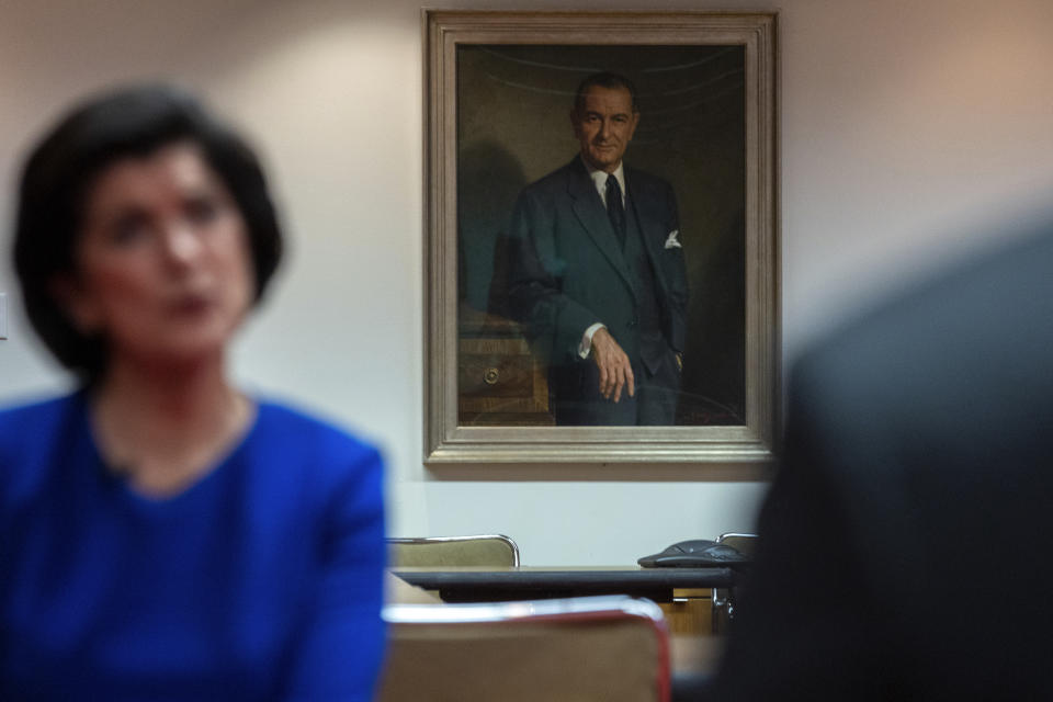 A portrait of President Lyndon B. Johnson hangs over the shoulder of Luci Baines Johnson as she recounts stories of her father at the LBJ Presidential Library, May 16, 2023, in Austin, Texas. (AP Photo/Stephen Spillman)