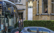 A woman claps from her window as a bus delivers a loudspeaker message from family and friends in Brussels, Wednesday, April 22, 2020. With streets in the Brussels capital mostly devoid of loud traffic and honking horns, a simple piece of emotional poetry can split the air. The public bus company, STIB-MIVB, has been calling on people to send in voice messages, which are now delivered by a special bus driving in a loop to connect all the messages and leave a trail of happiness. (AP Photo/Olivier Matthys)