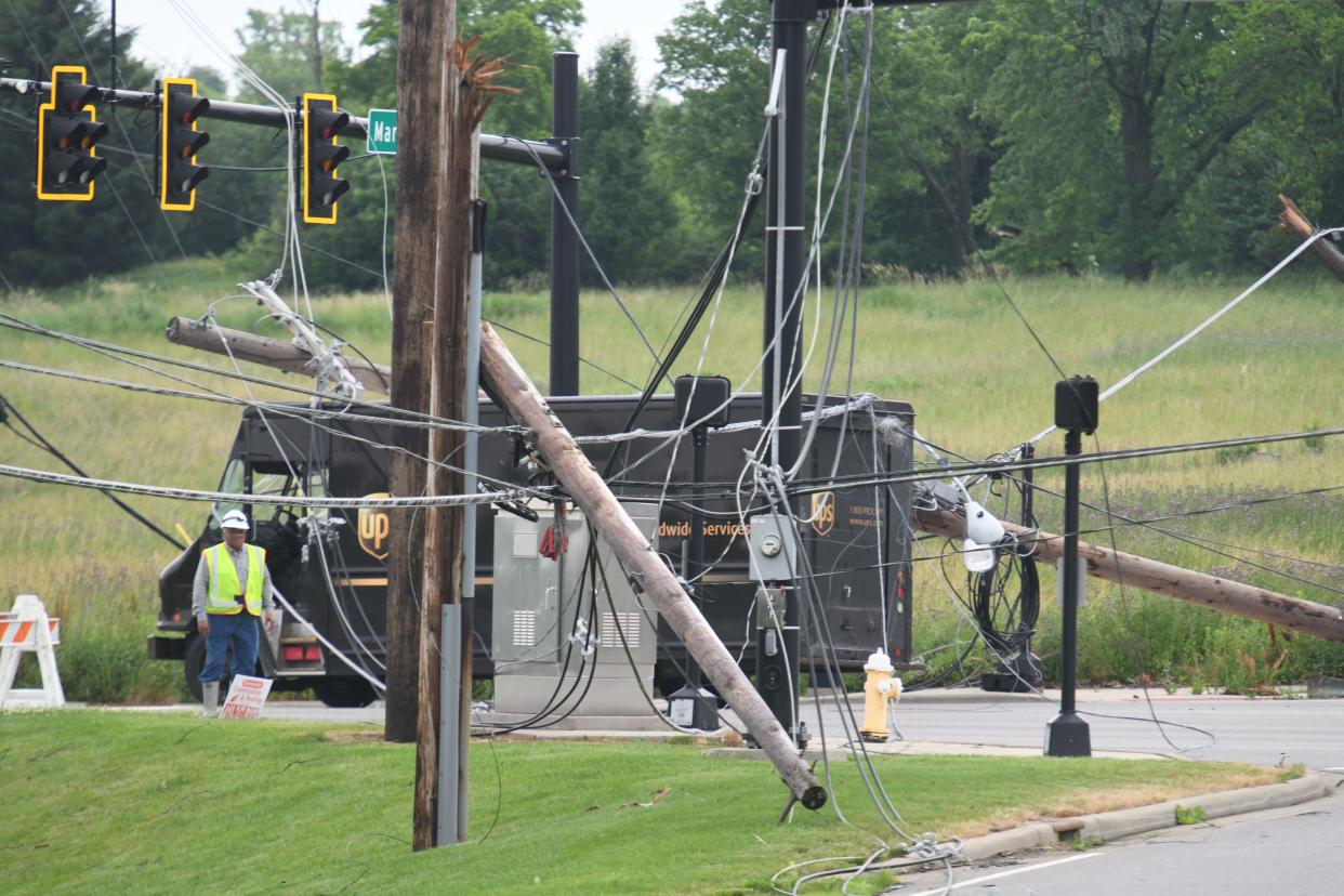 Utility workers try to figure out how to free a UPS truck tangled in power lines at the corner of Marion Avenue and Trimble Road on Tuesday morning. The power lines came down during the overnight storm and landed on the delivery vehicle.