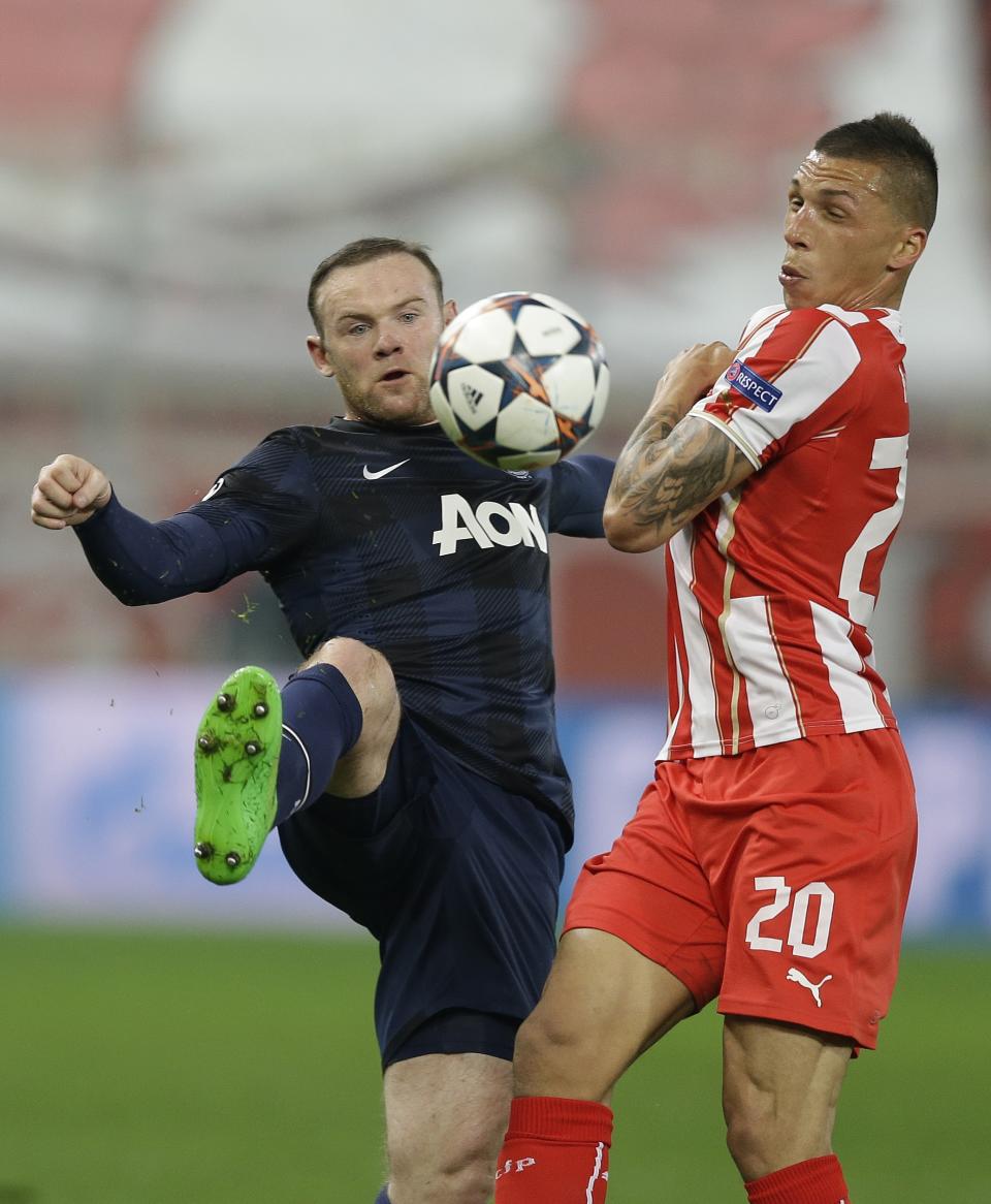 Olympiakos' Jose Holebas, right, fights for the ball with Manchester United's Wayne Rooney during their Champions League, round of 16, first leg soccer match at Georgios Karaiskakis stadium, in Piraeus port, near Athens, on Tuesday, Feb. 25, 2014. (AP Photo/Thanassis Stavrakis)