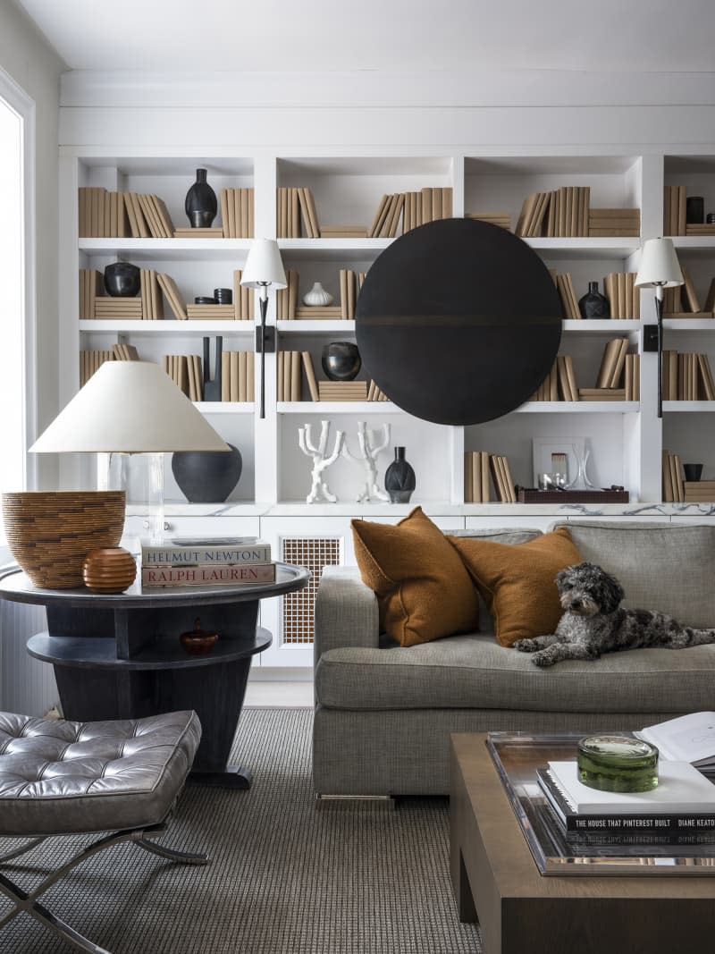 Living room with gray sofa with dog and wall of white built in bookshelves