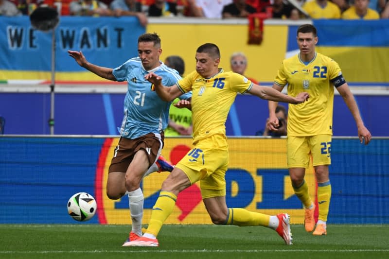 Belgianul Timothy Castagne (stânga) și ucraineanul Vitaly Mikulenko se luptă pentru minge în timpul meciului de fotbal Euro 2024 din Grupa E dintre Ucraina și Belgia de la Stuttgart Arena.  Marianne Murat/dpa