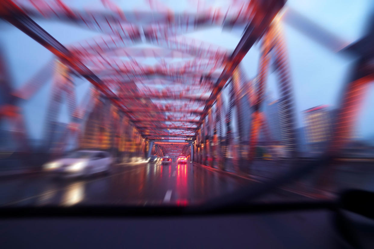 Driving a car across a bridge in the rain at night Getty Images/Yaorusheng