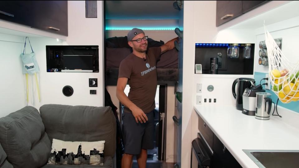 A man shows off the inside of his "stealth studio van," which has a kitchen, bedroom, and office.