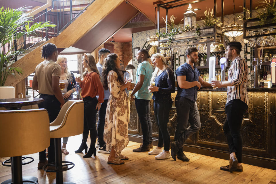 Group of people socializing at a bar with a bartender serving drinks