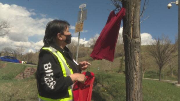 Members of Calgary's Bear Clan Patrol, an Indigenous community watch group, hang red dresses in advance of the National Day of Awareness for Missing and Murdered Indigenous Women and Girls. (Dave Gilson/CBC - image credit)