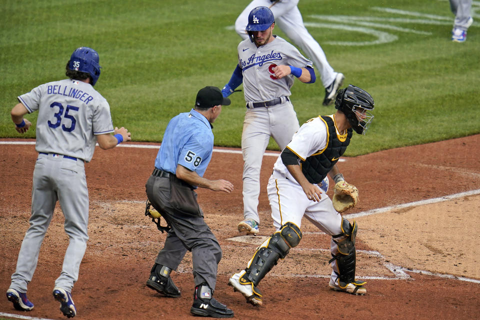Los Angeles Dodgers' Cody Bellinger, left, watches, after scoring, as Gavin Lux, center, scores as Pittsburgh Pirates catcher Jacob Stallings, right, waits for the late relay throw during the third inning of a baseball game in Pittsburgh, Thursday, June 10, 2021. Umpire is Dan Iassogna (58). (AP Photo/Gene J. Puskar)