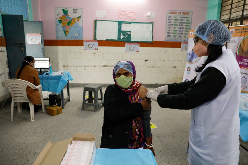 FILE PHOTO: A health worker and a volunteer take part in a nationwide trial run of coronavirus disease (COVID-19) vaccine delivery systems, inside a school, which has been converted into a temporary vaccination centre, in New Delhi