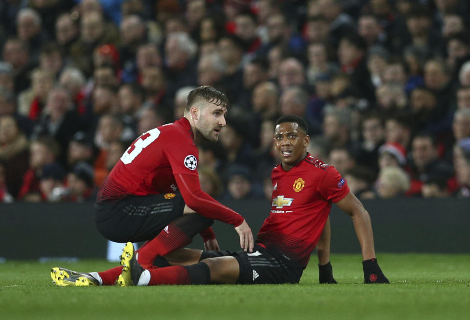 Manchester United's Luke Shaw, left, speaks to Manchester United's Anthony Martial who is injured during the Champions League round of 16 soccer match between Manchester United and Paris Saint Germain at Old Trafford stadium in Manchester, England, Tuesday, Feb. 12,2019.(AP Photo/Dave Thompson)