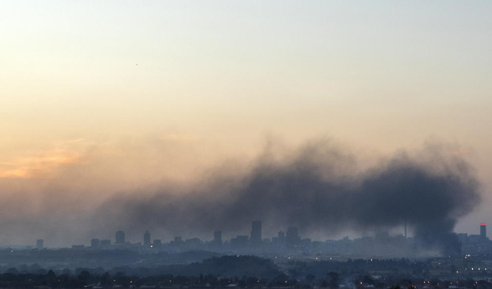 Smoke covers the Johannesburg skyline as people protests in downtown area, in Johannesburg, South Africa, Sunday, July 11, 2021. Protests have spread from the KwaZulu Natal province to Johannesburg against the imprisonment of former South African President Jacob Zuma who was imprisoned last week for contempt of court. (AP Photo/Themba Hadebe)