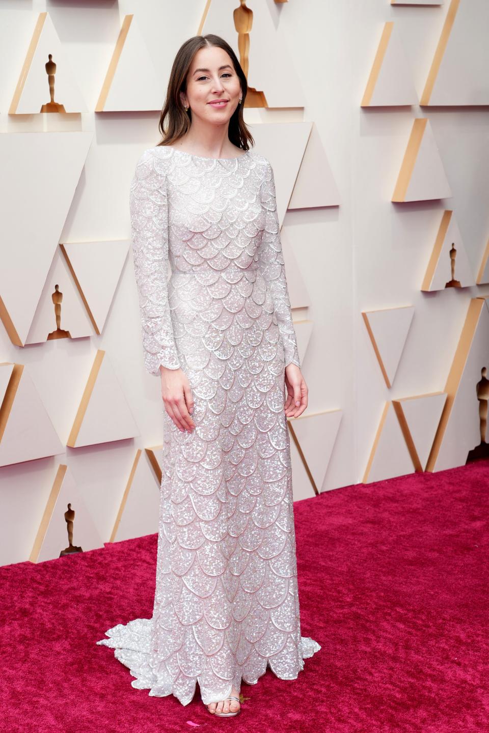 Alana in a white silver high neck long sleeve gown with a scale pattern on it.