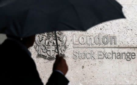 A man shelters under an umbrella as he walks past the London Stock Exchange in London, Britain August 24, 2015. REUTERS/Suzanne Plunkett