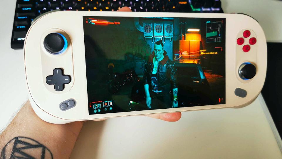 Hand holding Ayaneo 2S with Cyberpunk 2077 gameplay on screen