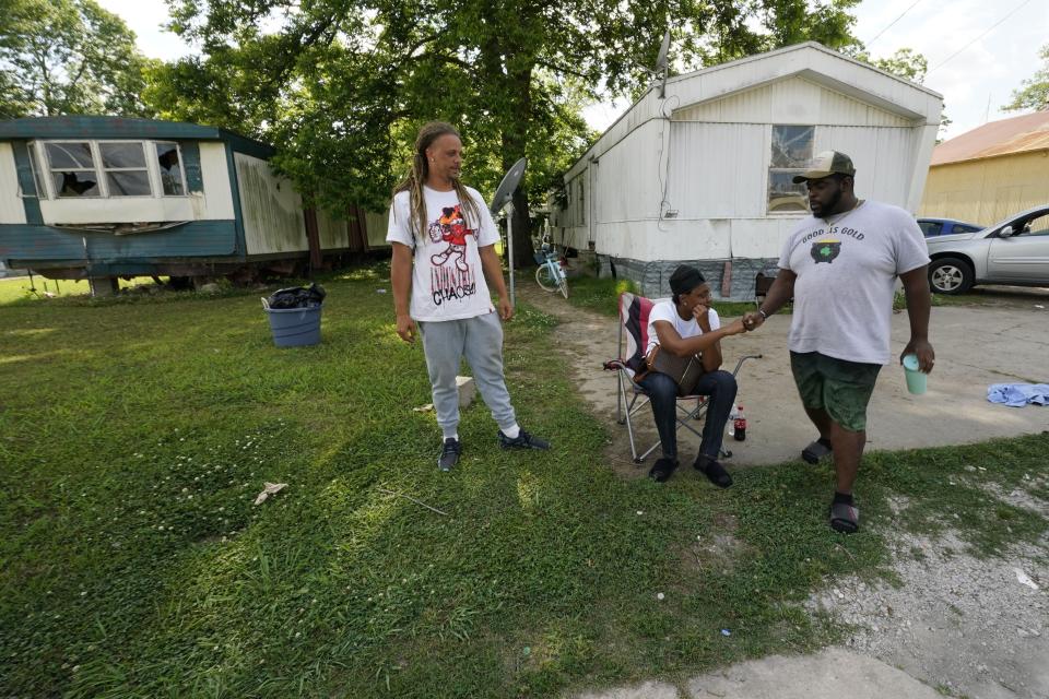 Mildred Joyner, seated, and her brother Antonio Joyner, left, who were in their mobile home when a deadly tornado destroyed it, are greeted by friend Jay Newell, outside her aunt's mobile home that sustained damage, in Rolling Fork, Miss., Friday, May 19, 2023. The tornado hit Joyner's mobile home so hard she felt it shake, heard the cracking sound of what she figured was her home coming apart and then she woke up in the hospital. (AP Photo/Gerald Herbert)