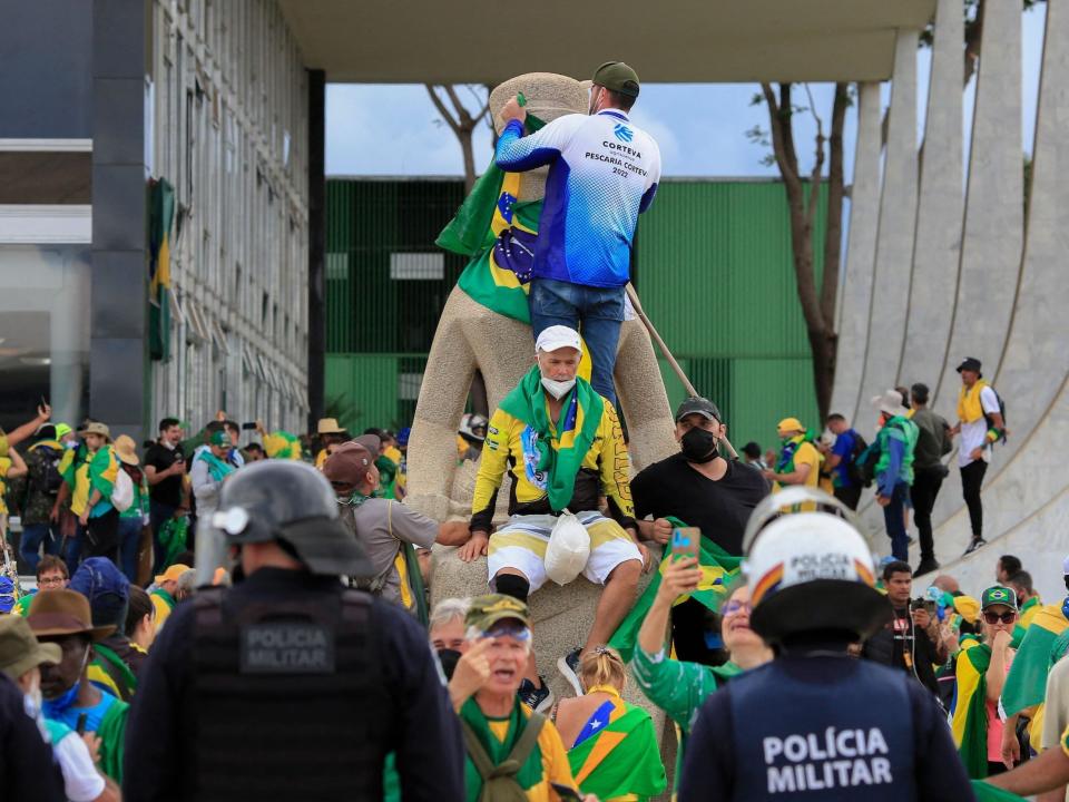 Supporters of Brazilian former President Jair Bolsonaro tie a flag on the head of a statue outside Brazil's Congress.