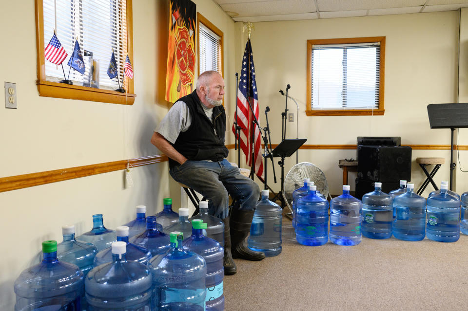 A town meeting attendee sits among water jugs donated to residents by the Center for Coalfield Justice in New Freeport, Pa., in March. (Justin Merriman for NBC News)