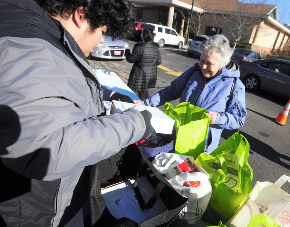 A volunteer smiles as John Lupack, a New Jersey Youth Corps student, packs freshly baked pumpkin pies into bags to be distributed to those in need this holiday season at Project Self-Sufficiency in Newton on Monday, Nov. 21, 2022.