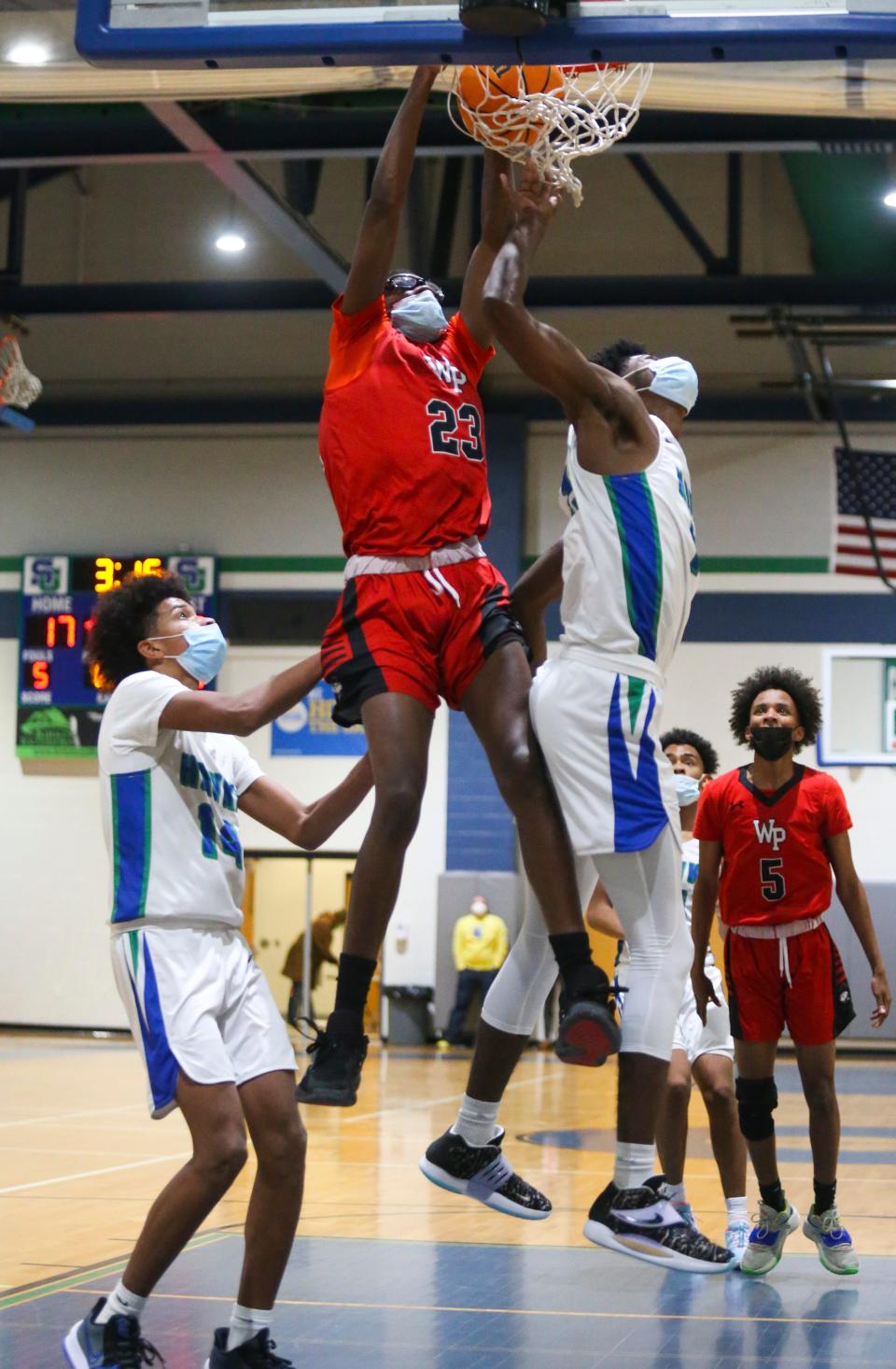 William Penn's Jordan Moore throws down a slam while drawing a foul for a three point play between St. Georges' Blair Thomas (left) and Jonathan Hardy in the Colonials' 54-49 win at St. Georges Thursday, January 6, 2022.