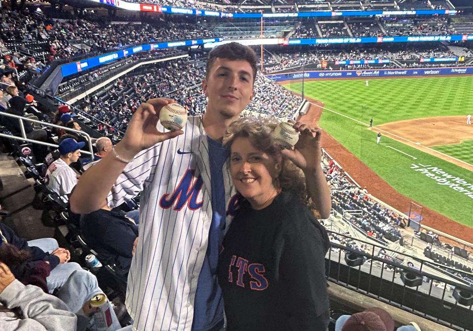 In a photo provided by Jerry Beach, Patrick Wedderburn, standing with his mother, Christa, holds two foul balls that he caught in a three-pitch span at the game between the Cincinnati Reds and the New York Mets on Friday.