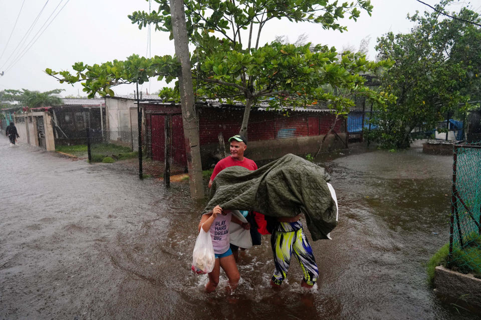People walk on a flooded street as Storm Idalia makes landfall in Cuba, Guanimar, Cuba, August 28, 2023.  REUTERS/Alexandre Meneghini