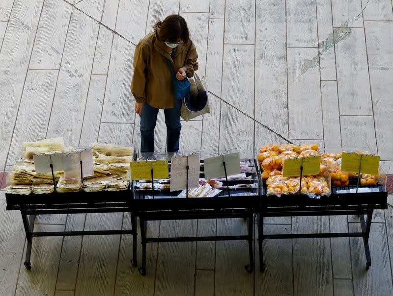 A woman chooses vegetables at a supermarket in Tokyo