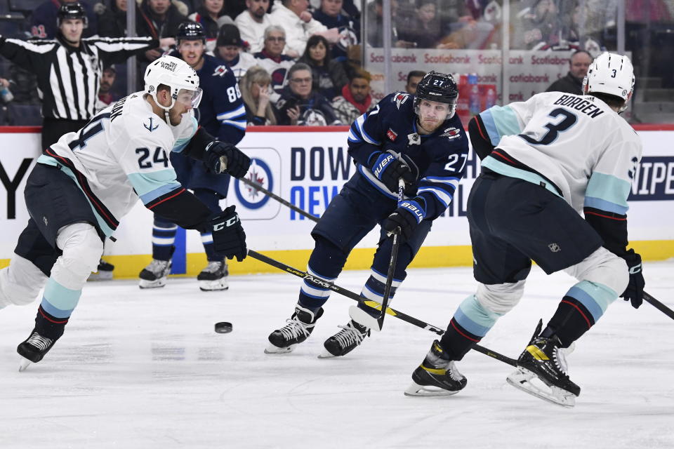 Winnipeg Jets' Nikolaj Ehlers (27) takes a shot between Seattle Kraken's Jamie Oleksiak (24) and Will Borgen (3) during the second period of an NHL game in Winnipeg, Manitoba on Tuesday Feb. 14, 2023. (Fred Greenslade/The Canadian Press via AP)