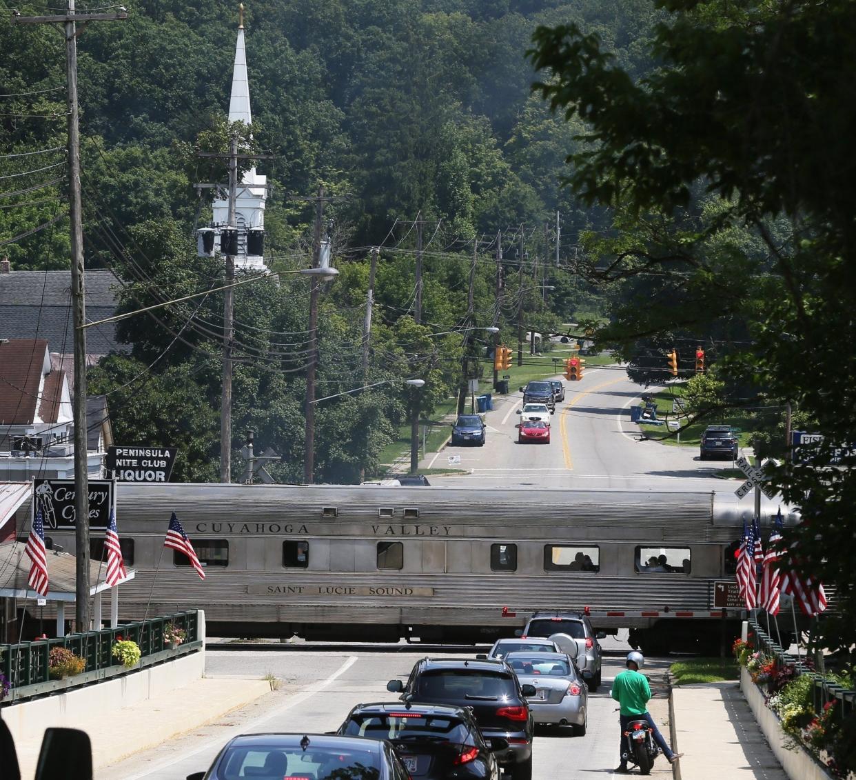 The Cuyahoga Valley Scenic Railroad train crosses State Route 303 through the heart of Peninsula, Ohio, on Wednesday, July 24, 2019. [Mike Cardew/Beacon Journal]