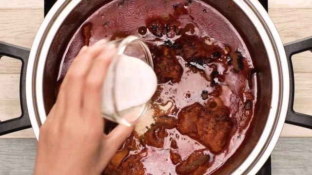 Adding coconut milk to rendang