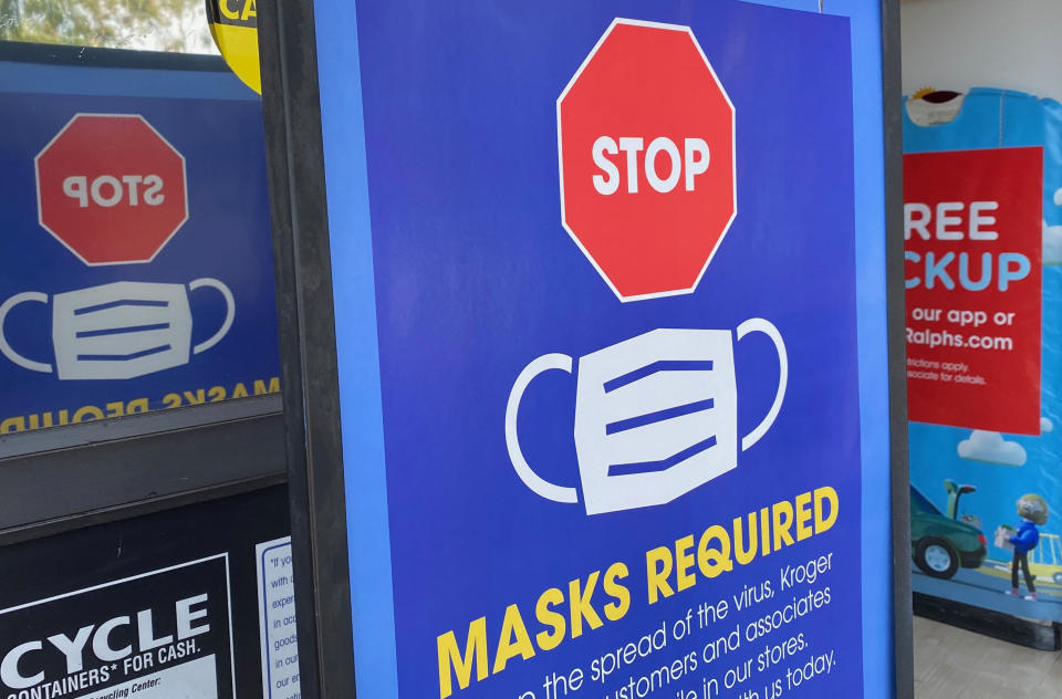 A sign at a store entrance reads: Stop, masks required.