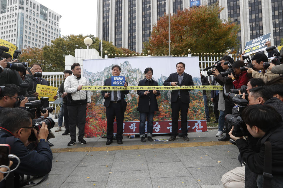 Protesters stand in front of an image of North Korea's Diamond Mountain as they stage a rally calling for the resumption of Diamond Mountain tourism in Seoul, South Korea, Monday, Oct. 28, 2019. South Korea on Monday proposed a face-to-face meeting with North Korea on the fate of a long-shuttered joint tourist project at a scenic North Korean mountain, as their relations remain cool over stalemated nuclear diplomacy. (AP Photo/Ahn Young-joon)