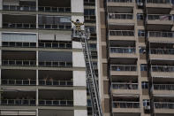 Firefighter Elielson Silva gestures to residents on their balconies as he plays his trumpet from the top of a ladder, during a lockdown to help contain the spread of the new coronavirus in Rio de Janeiro, Brazil, Sunday, April 5, 2020. “Everyone is suffering the pandemic and I’m trying to the boost the morale of Rio’s population, so all this difficulty is lessened in these times we’re going through,” says Silva, an 18-year veteran of the city's firefighting corps. “Bringing a bit of music, a bit of air, to these people has meant a lot to me as a musician and to the corps.” (AP Photo/Leo Correa)