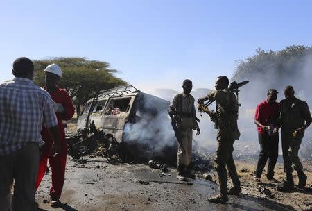 Somali government soldiers stand around the wreckage after a suicide car bomb explosion targeting peacekeeping troops in a convoy outside the capital Mogadishu September 8, 2014. REUTERS/Feisal Omar