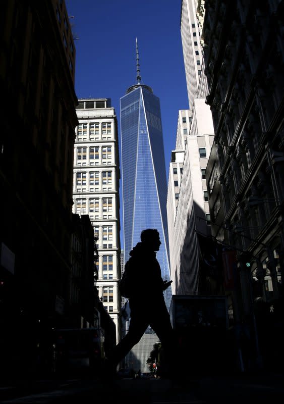 A man crosses the street in the shadows of One World Trade Center in New York City on November 3, 2014, as the building officially opens. File Photo by John Angelillo/UPI