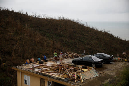 People stay at the roof of a damaged house after the area was hit by Hurricane Maria in Yabucoa, Puerto Rico September 22, 2017. REUTERS/Carlos Garcia Rawlins
