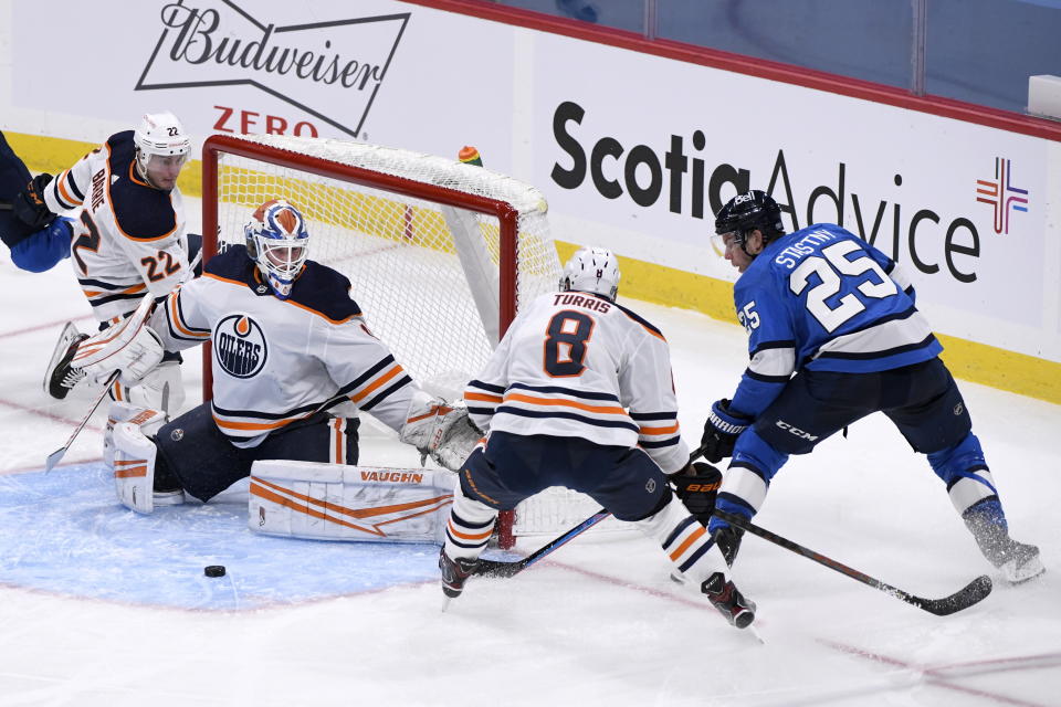 Edmonton Oilers goaltender Mikko Koskinen (19) makes a save on Winnipeg Jets' Paul Stastny (25) as Oilers' Kyle Turris (8) defends during the second period of an NHL hockey game, Sunday, Jan. 24, 2021 in Winnipeg, Manitoba. (Fred Greenslade/The Canadian Press via AP)