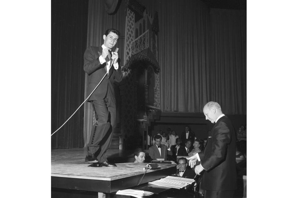 ARCHIVO - Eddie Fisher utiliza la parte superior de un piano de cola como escenario para entretener a 500 personas en una función previa al debut de su primera aparición en Las Vegas, en abril de 1957. Fisher inaugurará formalmente el nuevo Hotel Tropicana con un elenco de 50 artistas. (Foto AP, archivo)